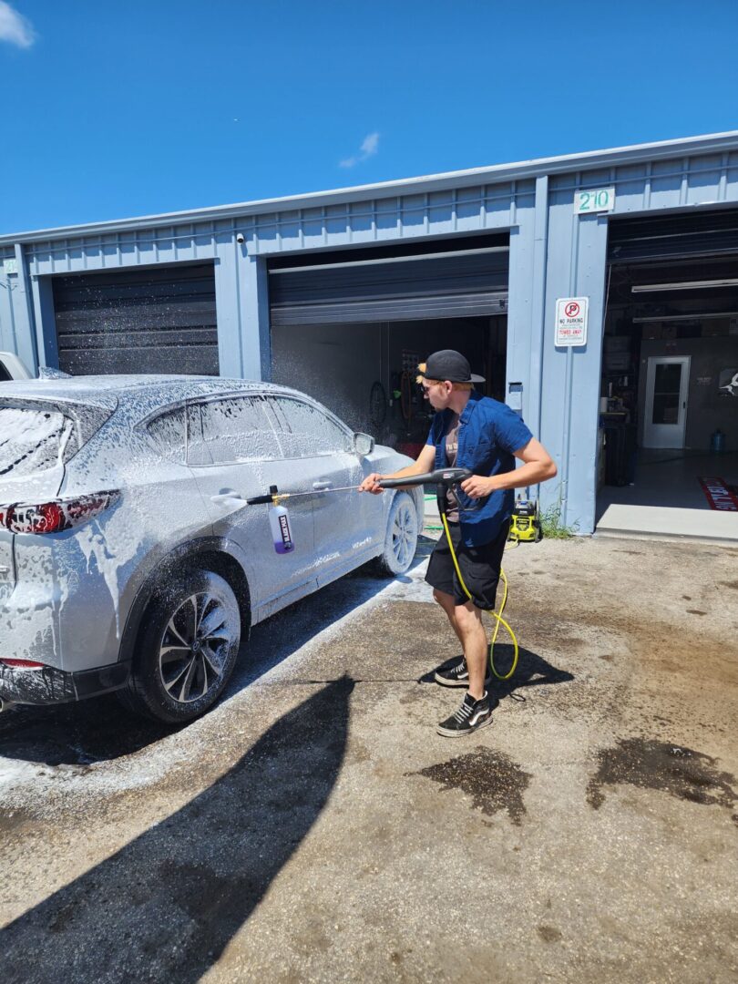 A man is washing his car in the driveway